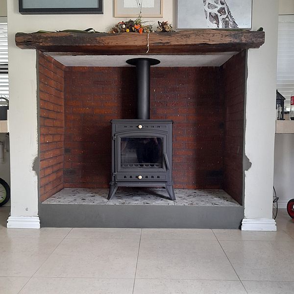 cast iron closed combustion stove installed in large hearth fireplace