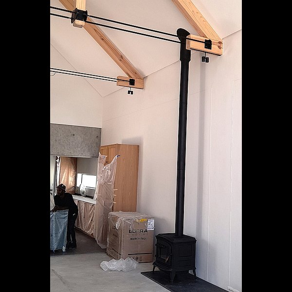 chimney sprayed black in open volume angled ceiling installation